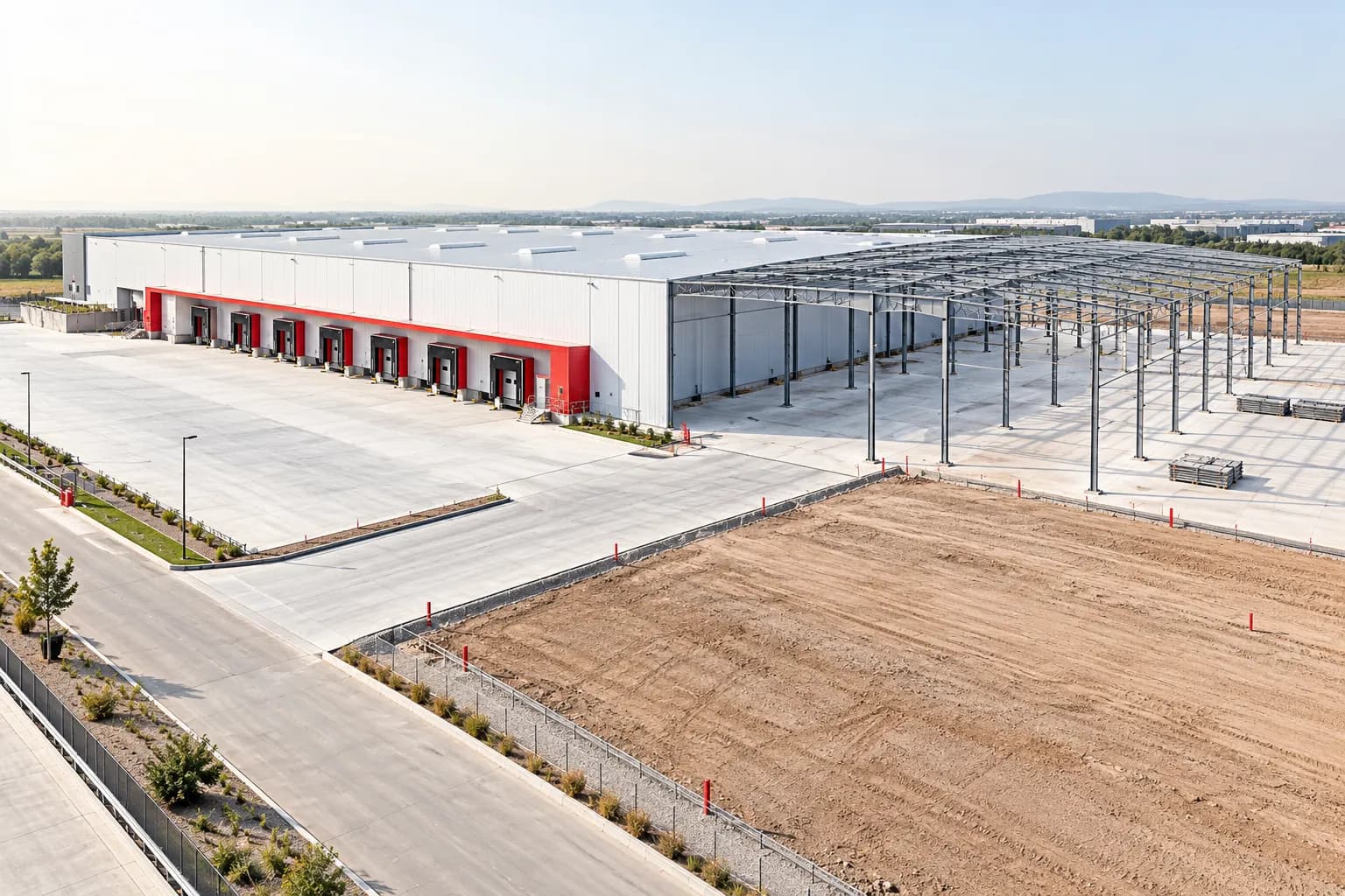 An industrial plot with a completed warehouse section and an adjacent steel structure under development.